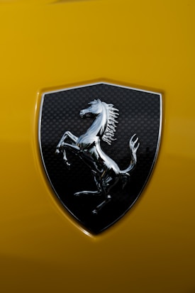 A chrome horse emblem set against a black carbon fiber background is prominently featured, surrounded by a bright yellow surface.