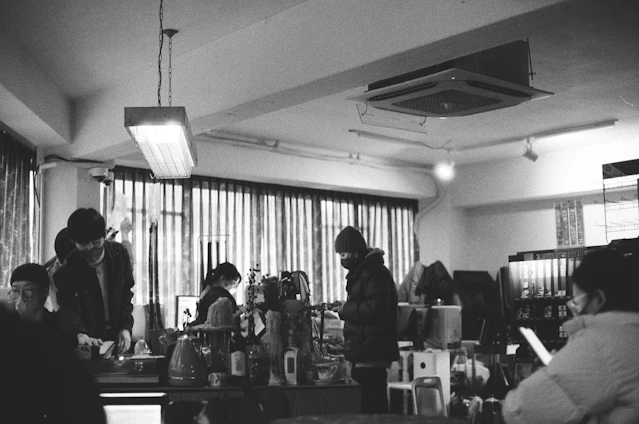A cozy cyber cafe interior with customers using computers and staff assisting with online forms.