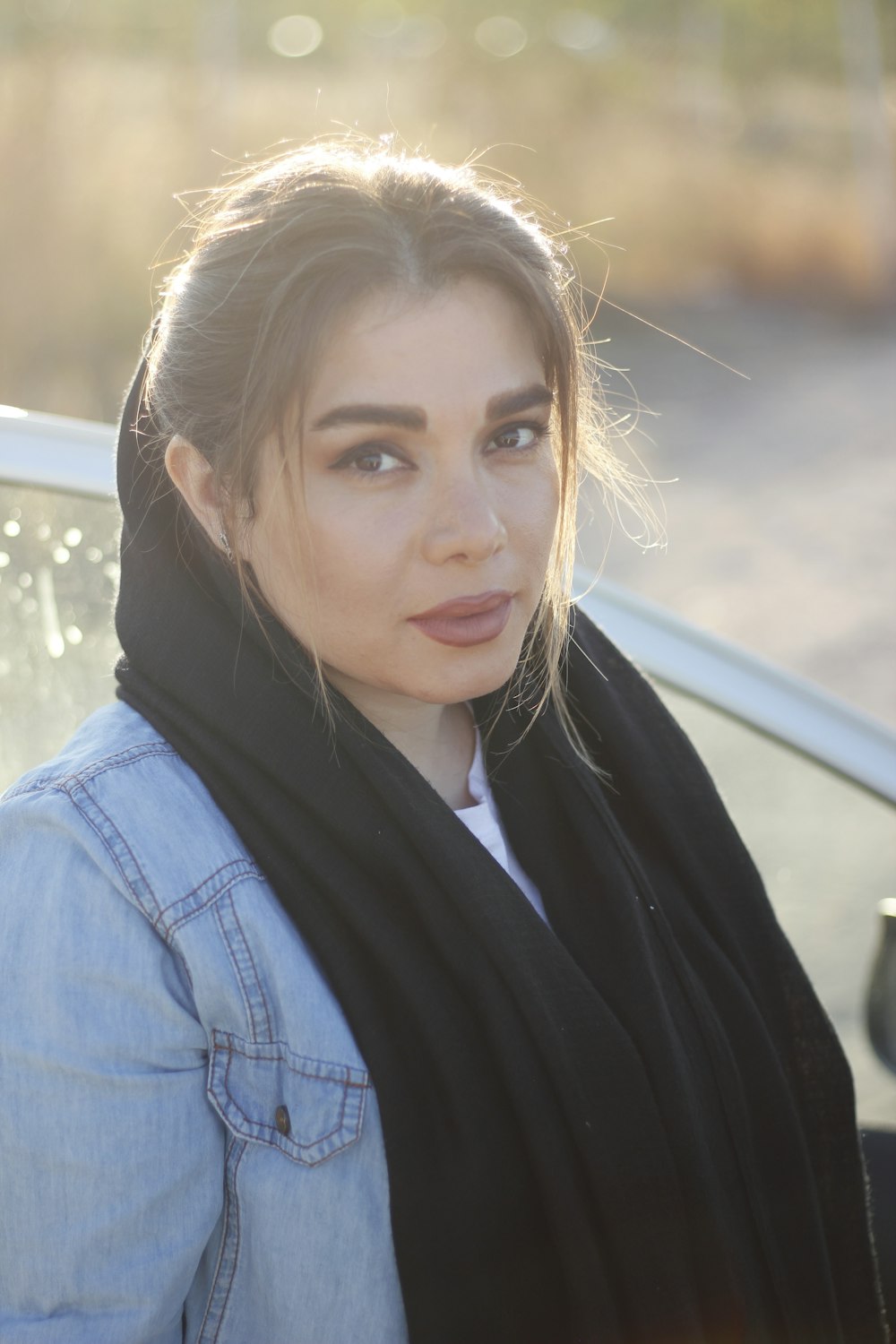 a woman standing next to a car wearing a scarf