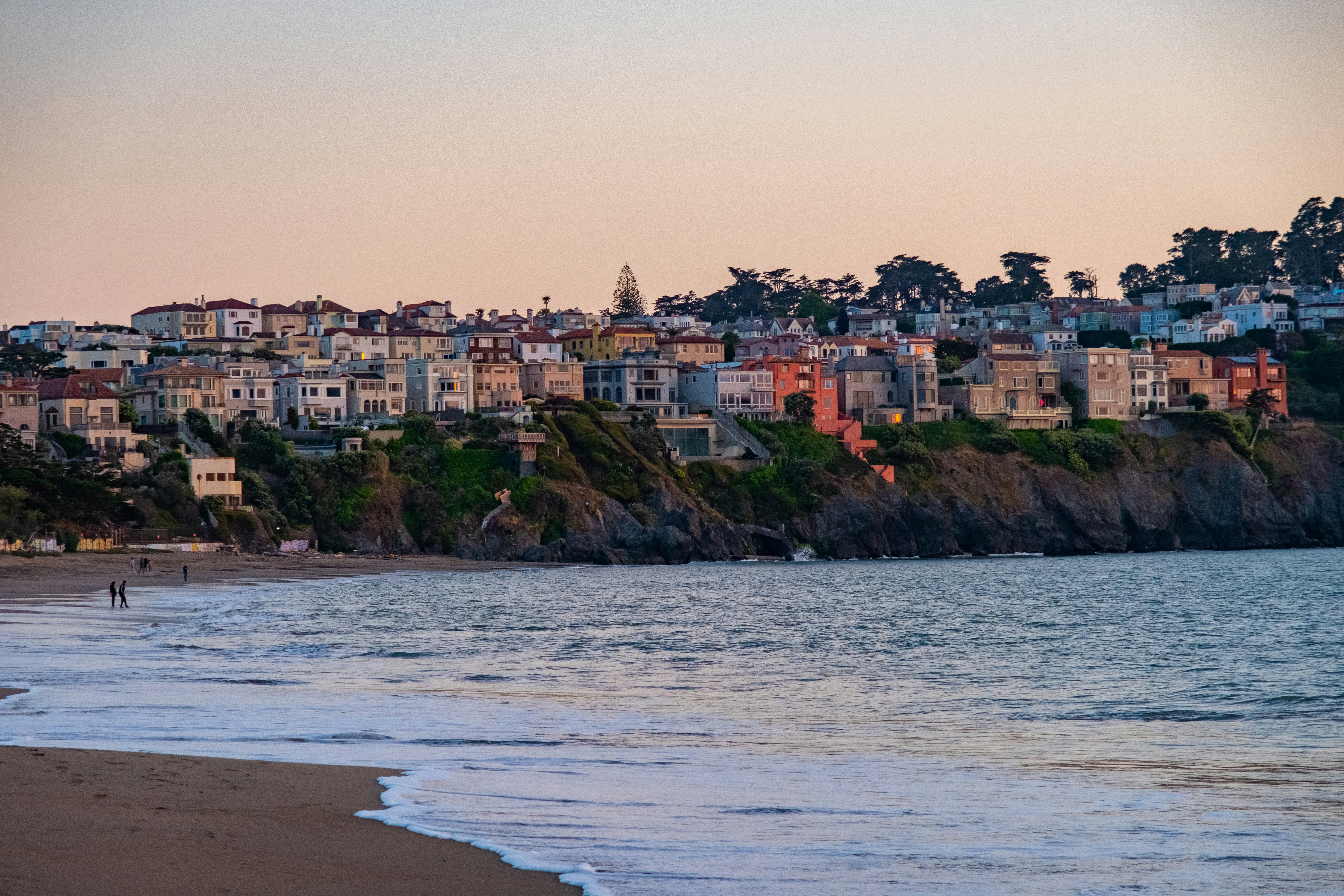 a beach with houses on a hill in the background, Cliffside Serenity: Nestled on the edge of San Francisco