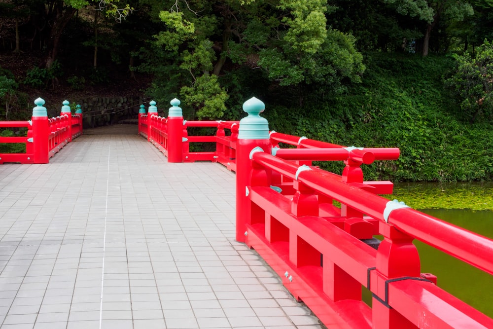 a walkway with red railings leading to a pond