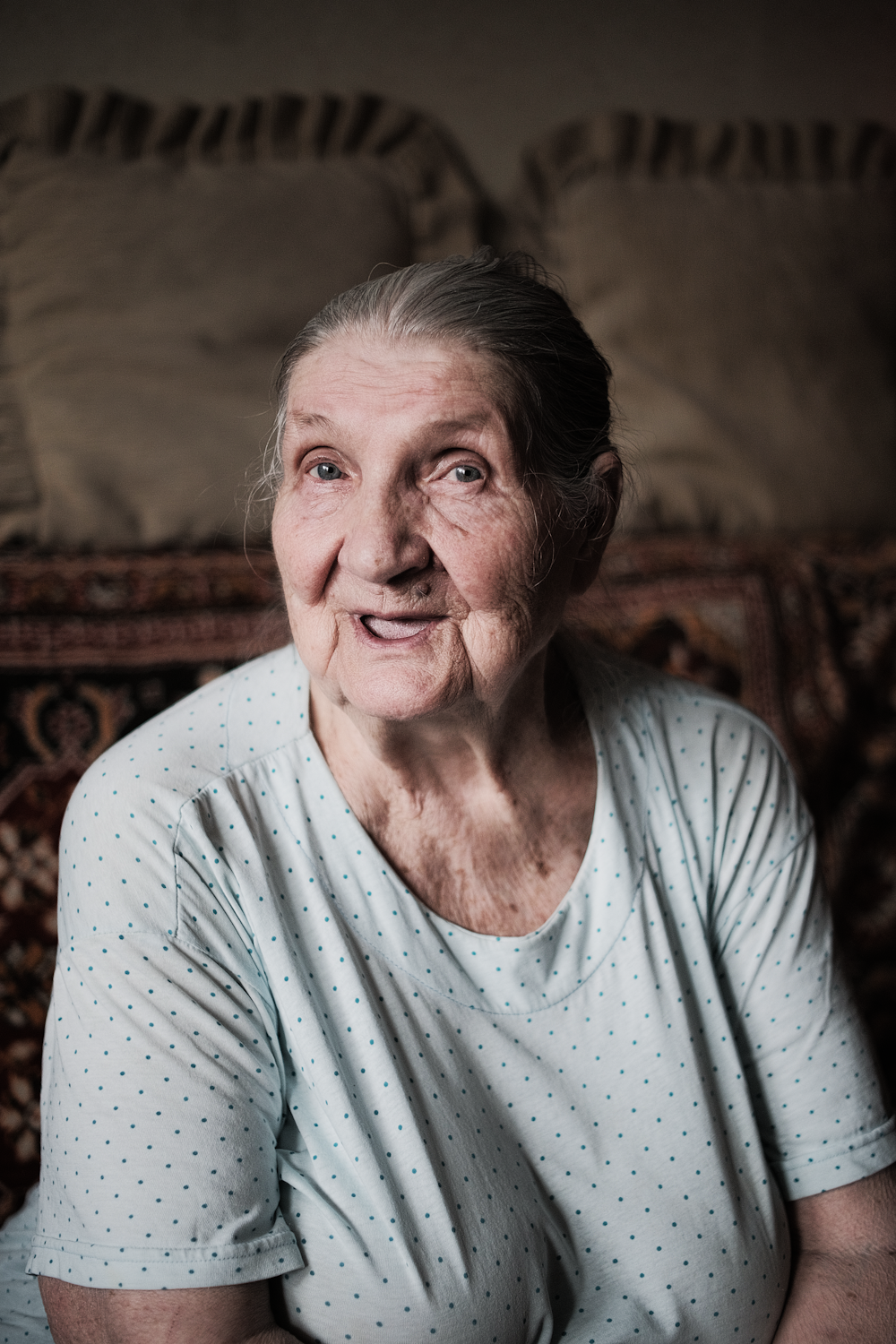 an older woman sitting in front of a bed