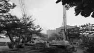 Aerial black and white photo of multiple construction vehicles working together on a large road project.