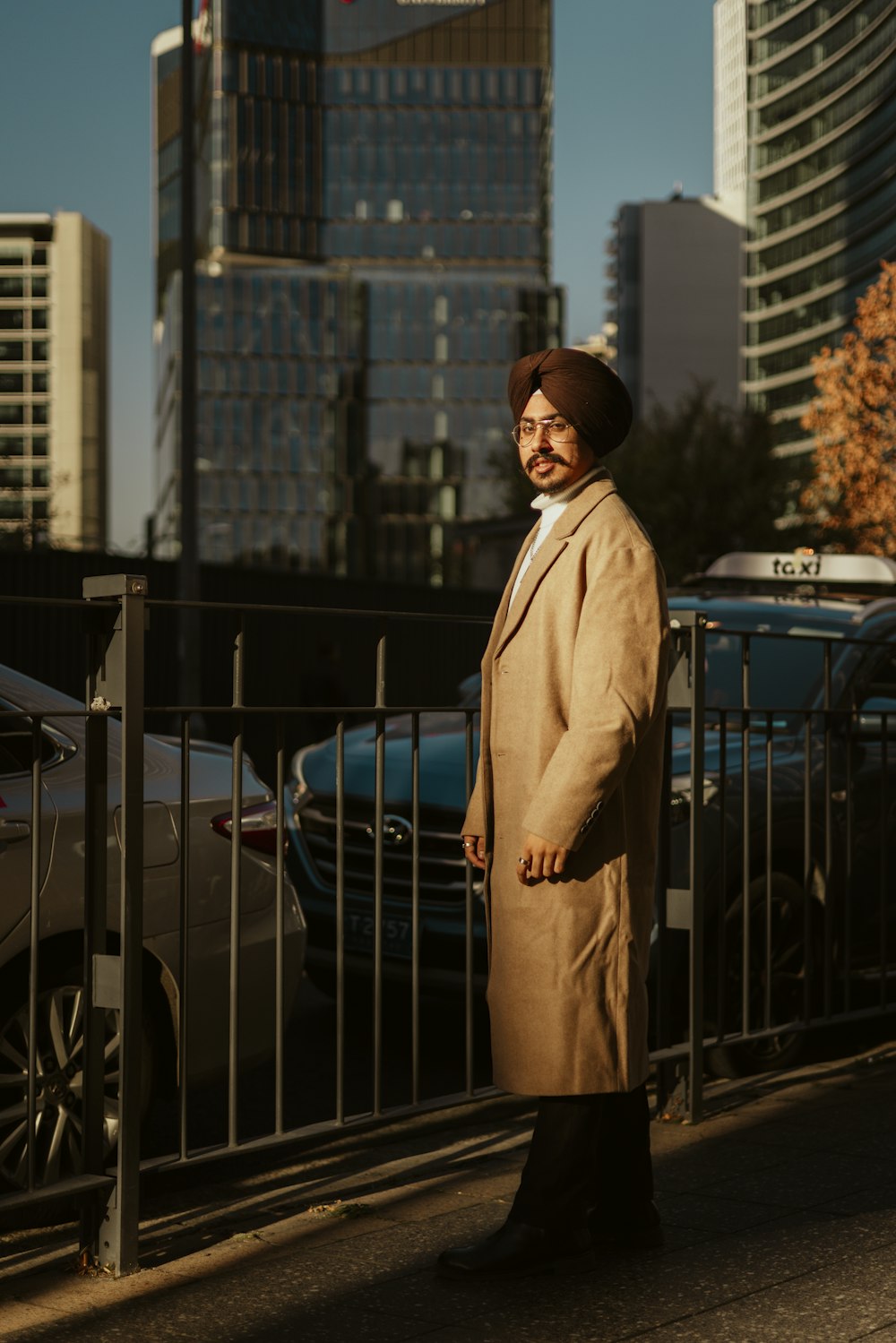 a man in a tan coat standing on a sidewalk