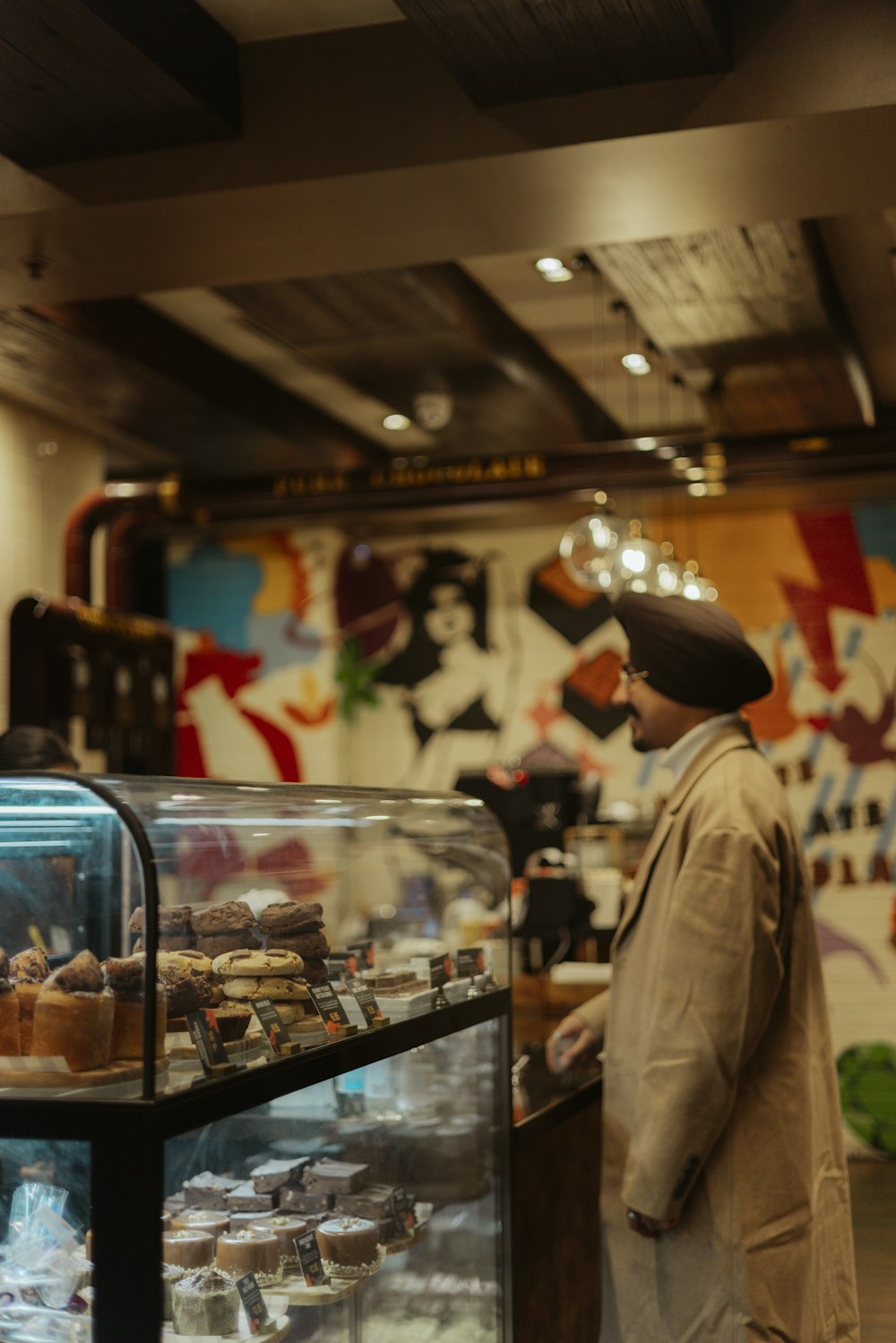 a man standing in front of a display case filled with pastries