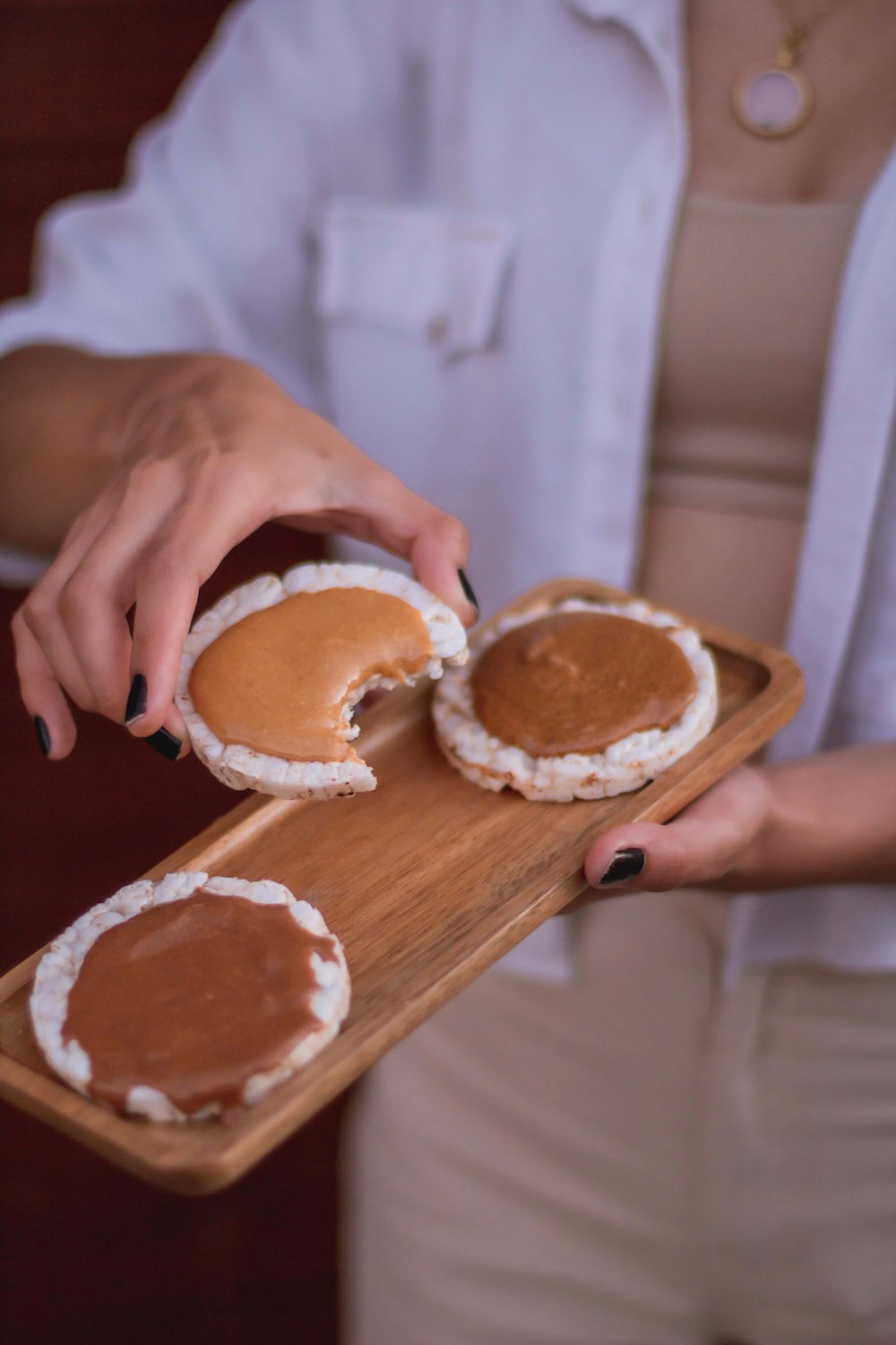 a woman holding a wooden tray with some food on it