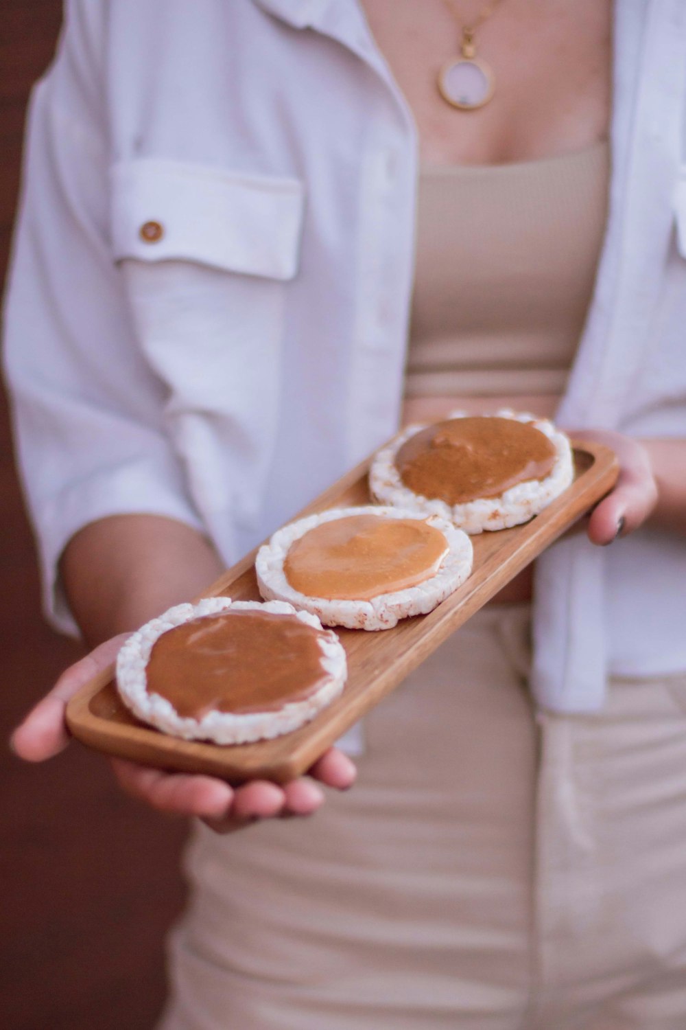 a woman holding a wooden tray with three cookies on it