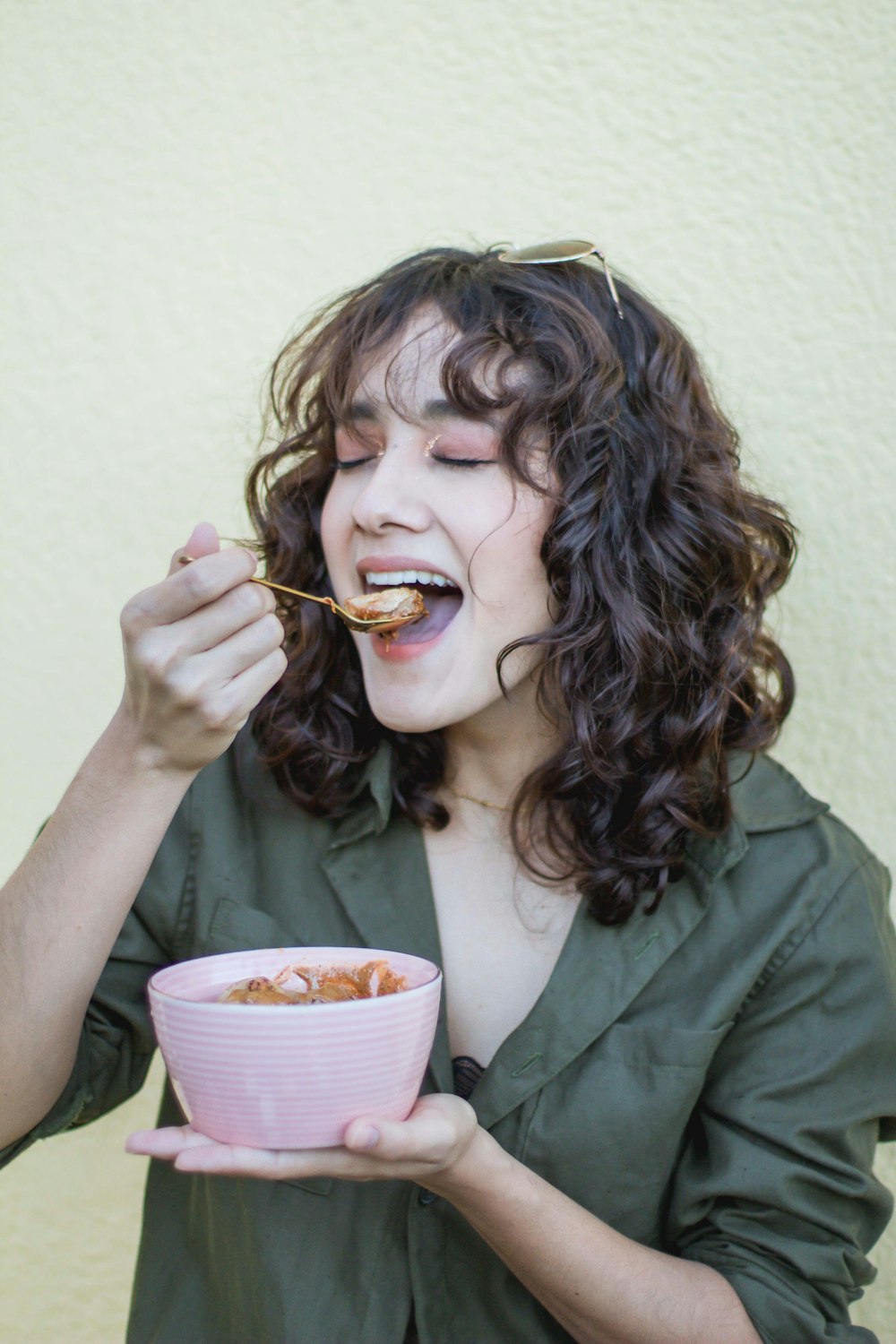 a woman eating food out of a pink bowl