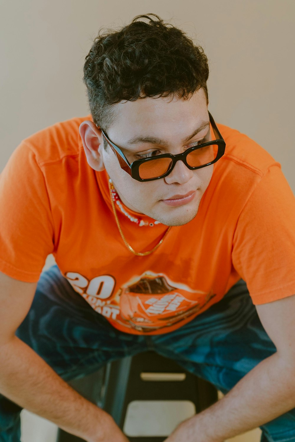 a man in an orange shirt is sitting on a chair