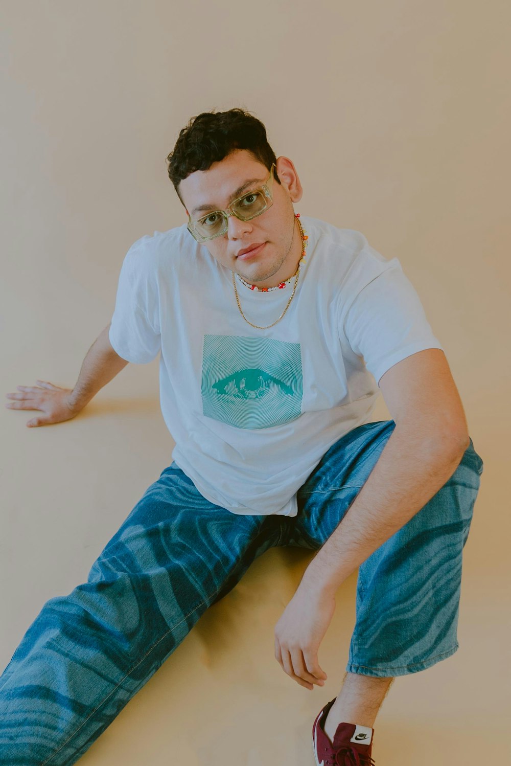 a man sitting on the ground wearing a t - shirt with an eye on it