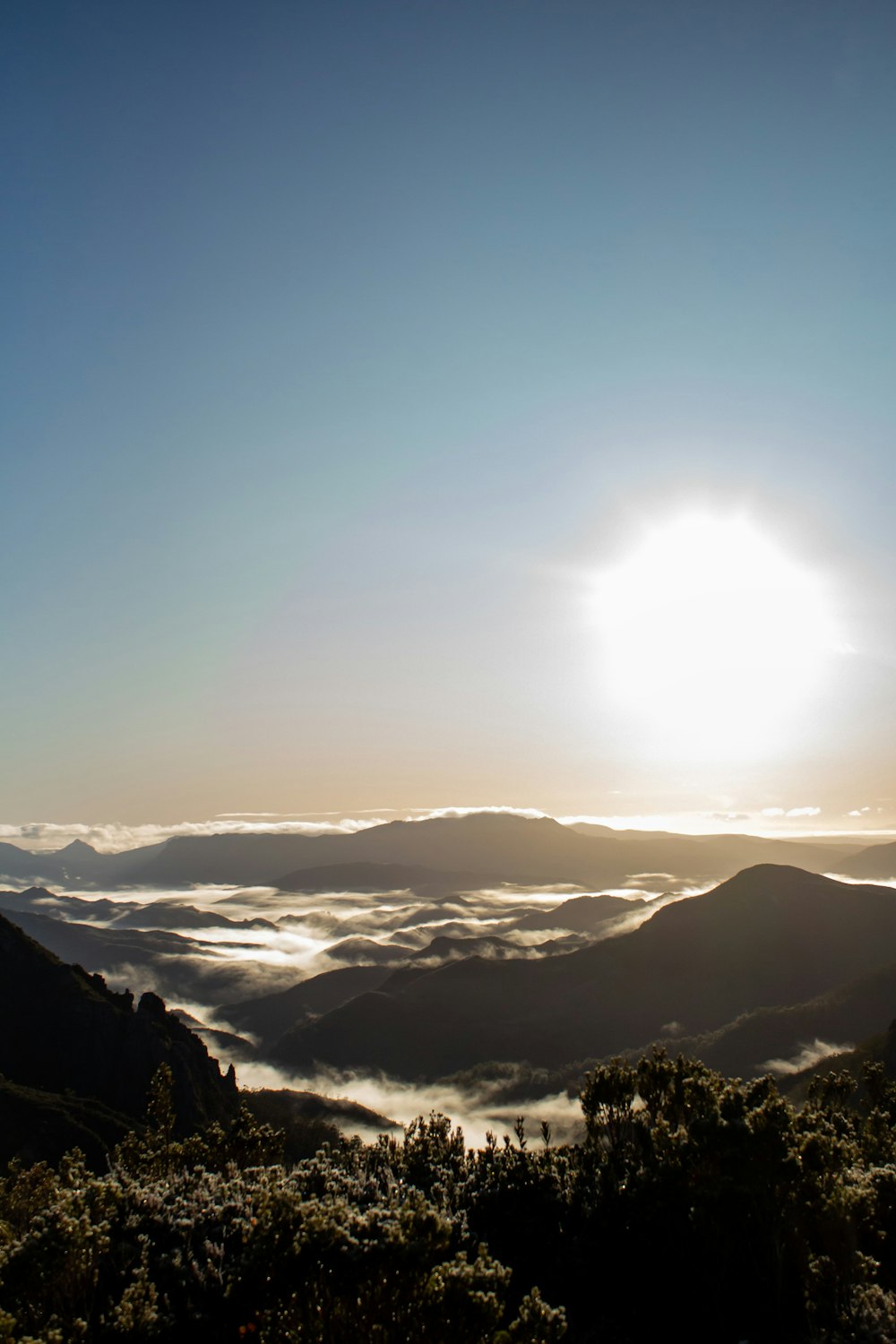 the sun is shining above the clouds in the mountains