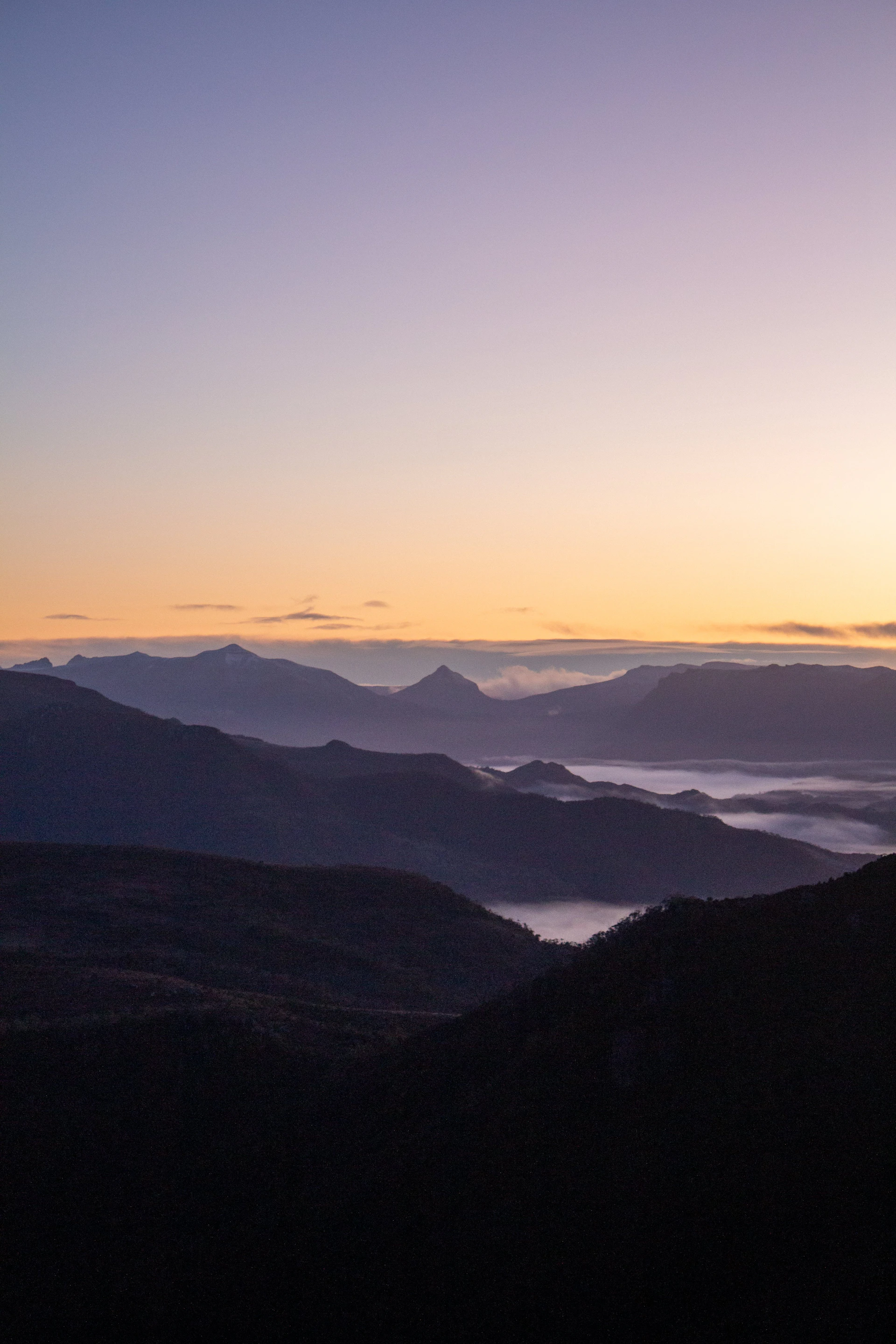 the sun is setting over a mountain range