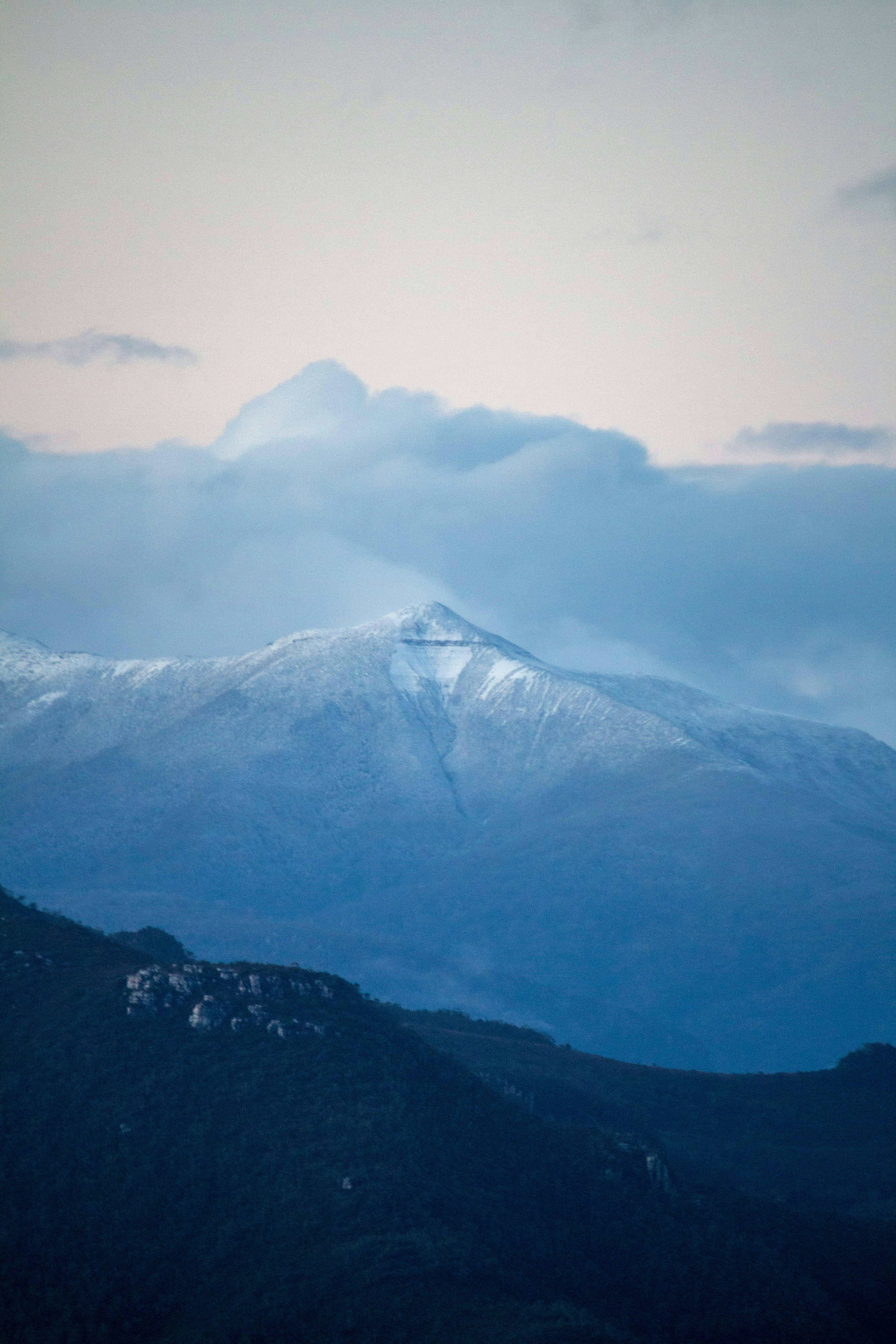 a mountain covered in snow under a cloudy sky
