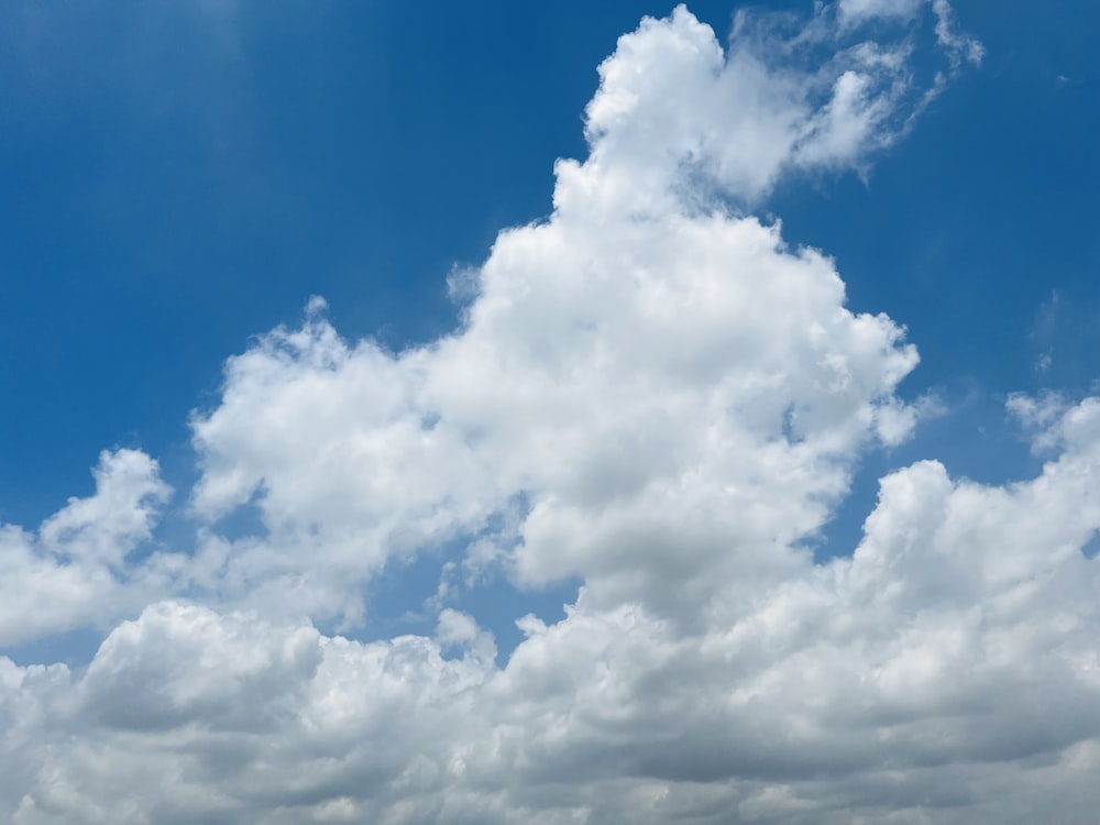 a plane flying through a cloudy blue sky