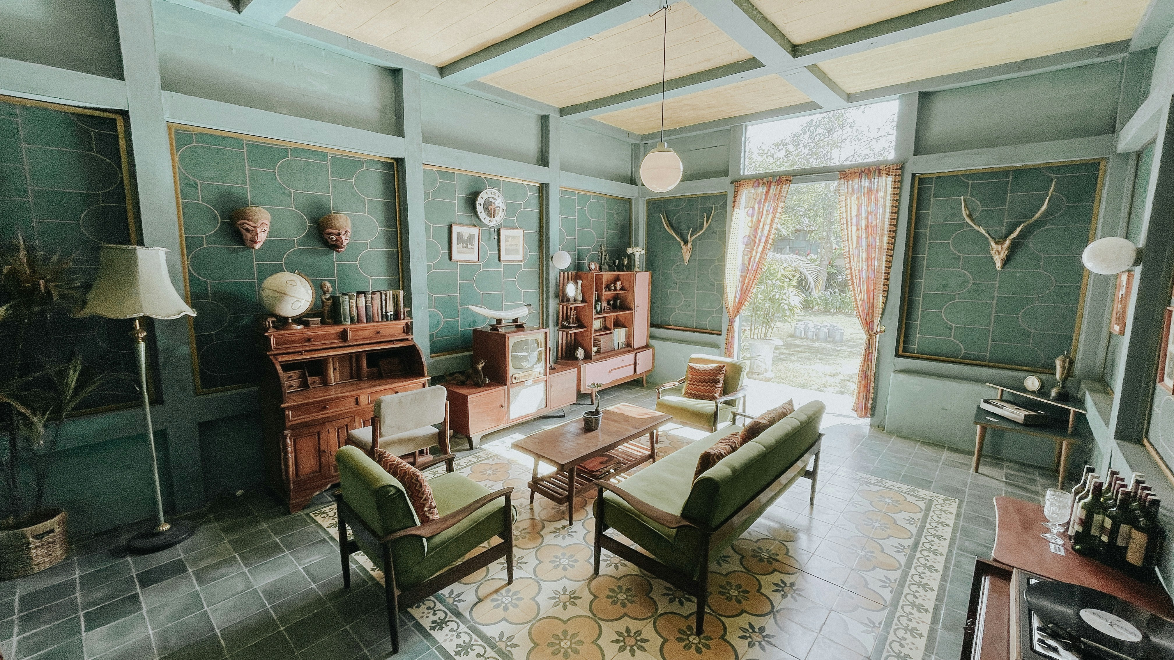 Cozy vintage living room with green sofas and teal geometric walls.