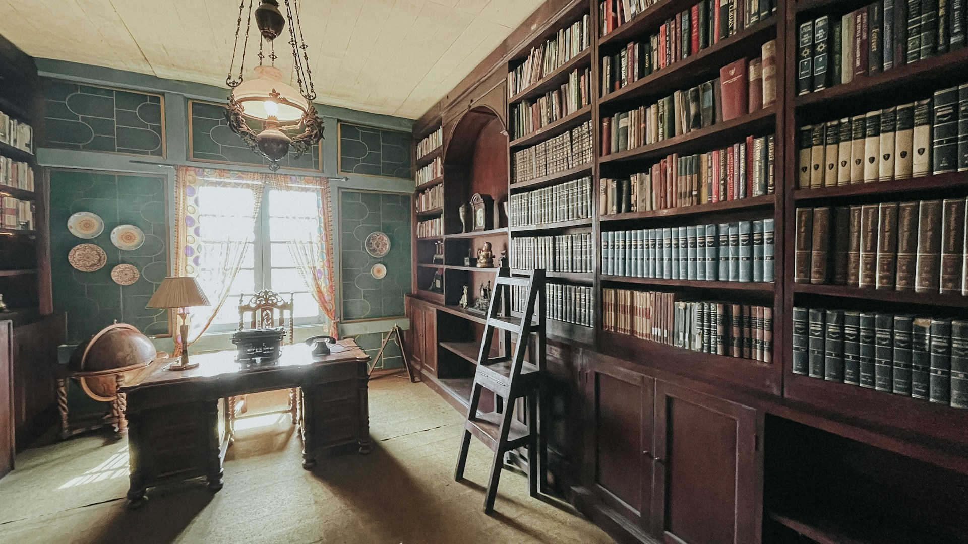 a room filled with lots of books and a desk