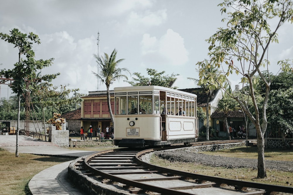 a trolley car traveling down tracks next to a tree