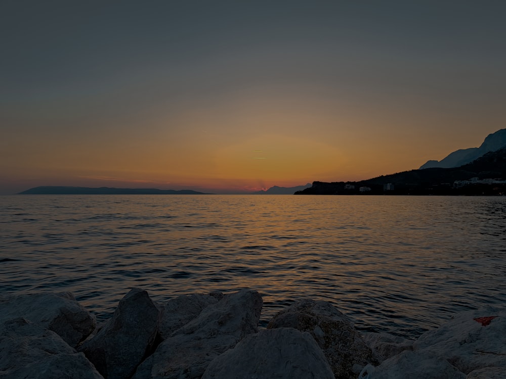 a sunset over a body of water with mountains in the background