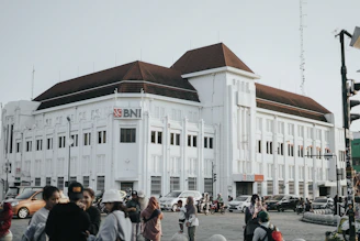 a large white building with a lot of people walking around it