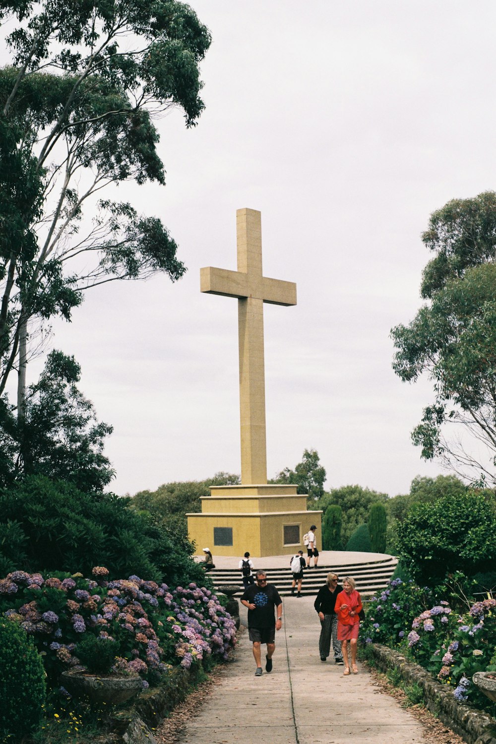 a group of people walking down a path towards a cross