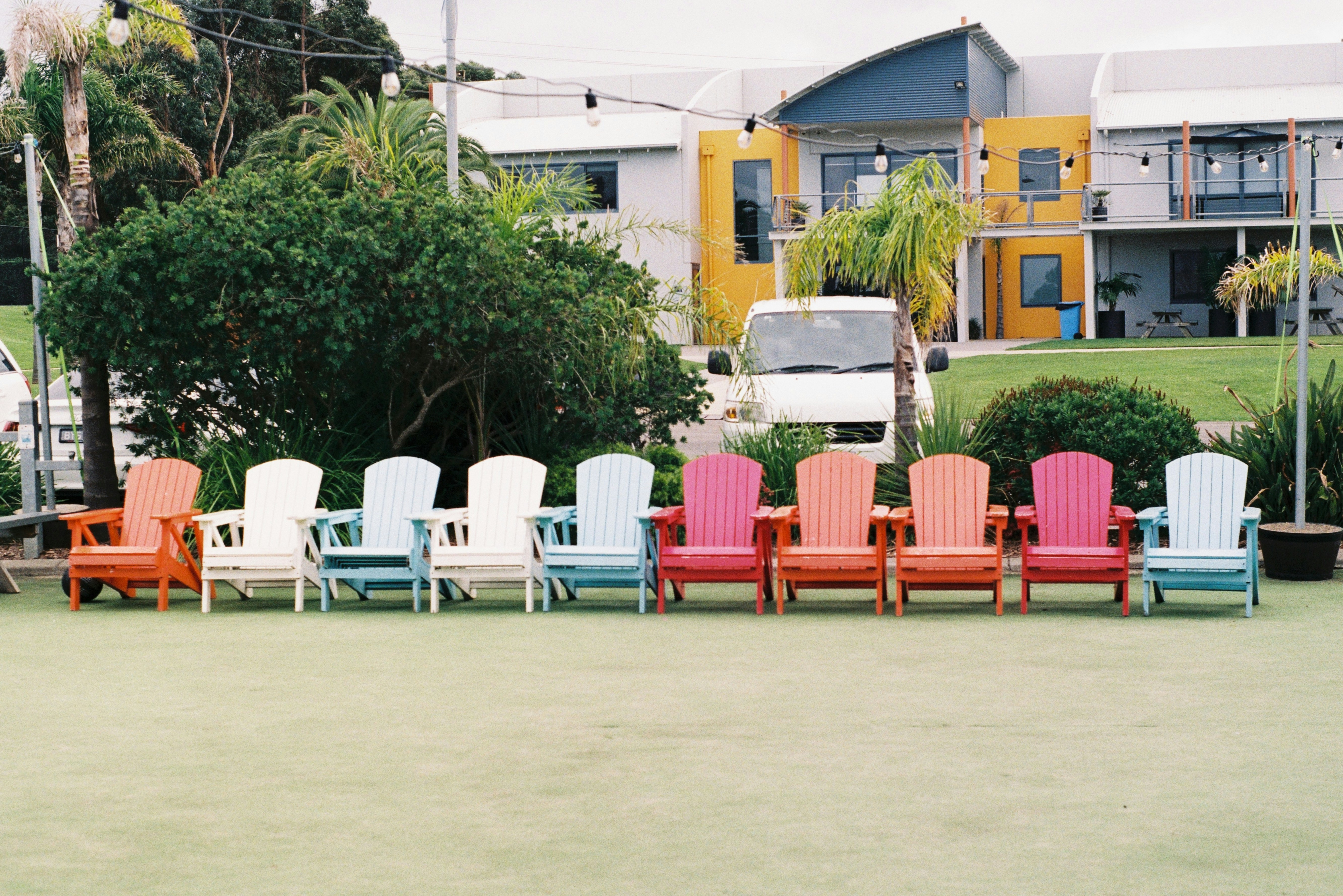 a row of lawn chairs sitting on top of a grass covered field