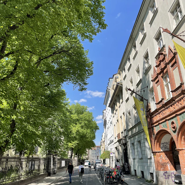 Two people walking down Sophienstrasse in Berlin past tall old buildings and an arched gateway