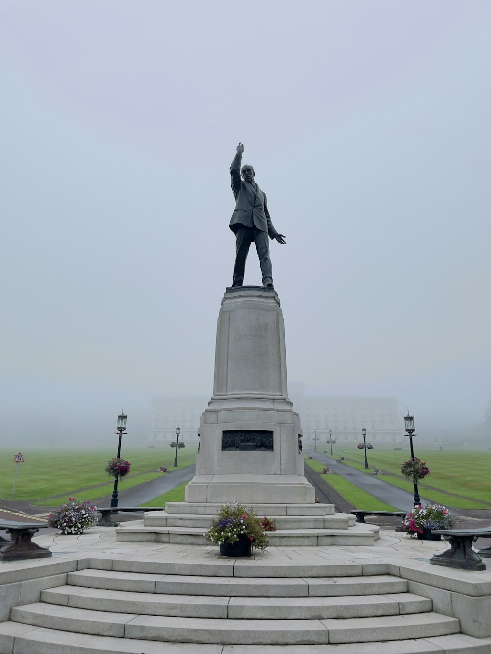 uma estátua de um homem em um pedestal em frente a um campo