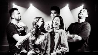 A group of friends laughing inside a sleek 360 photobooth with vibrant lighting.