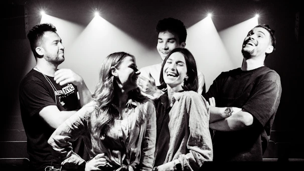 A group of friends laughing inside a sleek 360 photobooth with vibrant lighting.