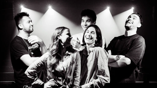 A vibrant photo of young people laughing together in a sunlit workshop space with colorful decor.