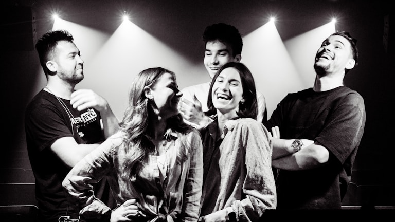 A group of anime friends laughing together in a lively, bright indoor setting with warm lights.