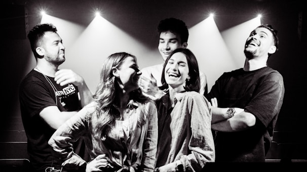 A lively group of friends laughing and posing inside a photobooth with colorful props.