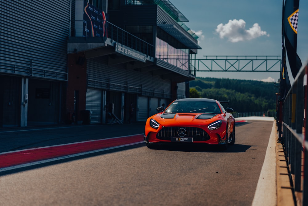 an orange sports car driving down a race track