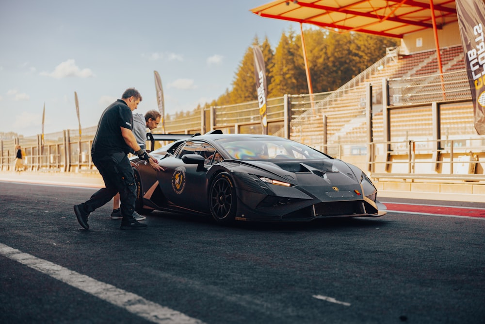 a man standing next to a black sports car