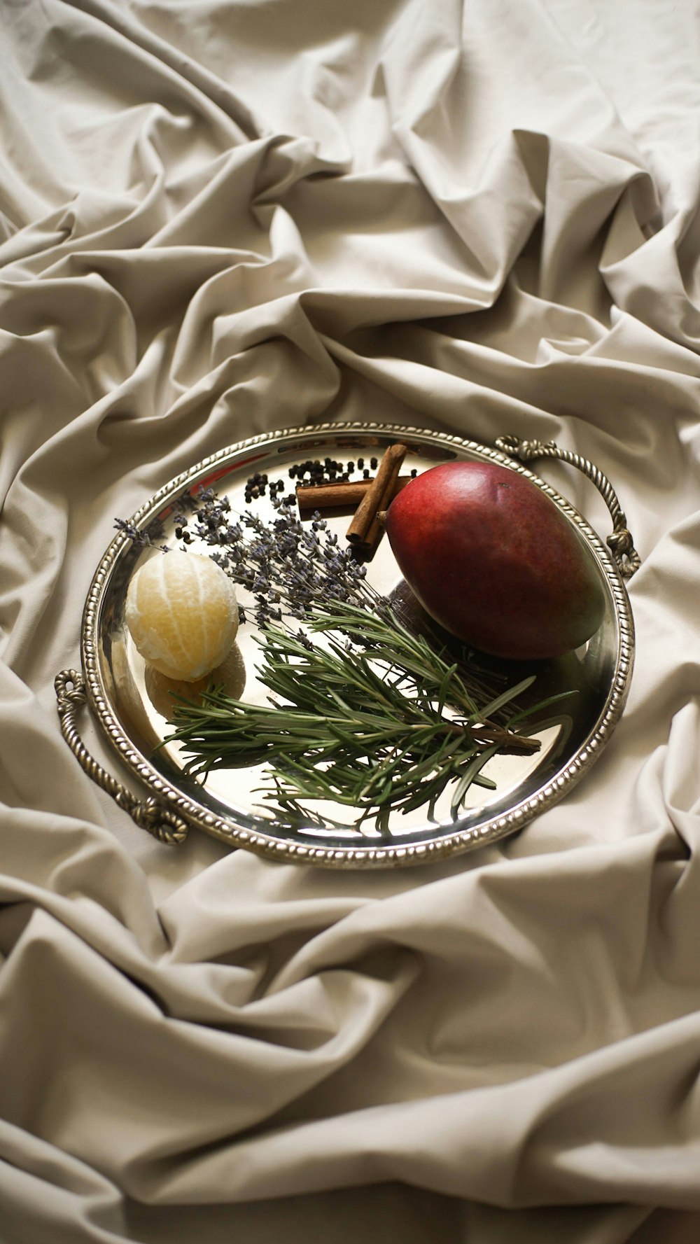 a silver plate topped with fruit on top of a bed