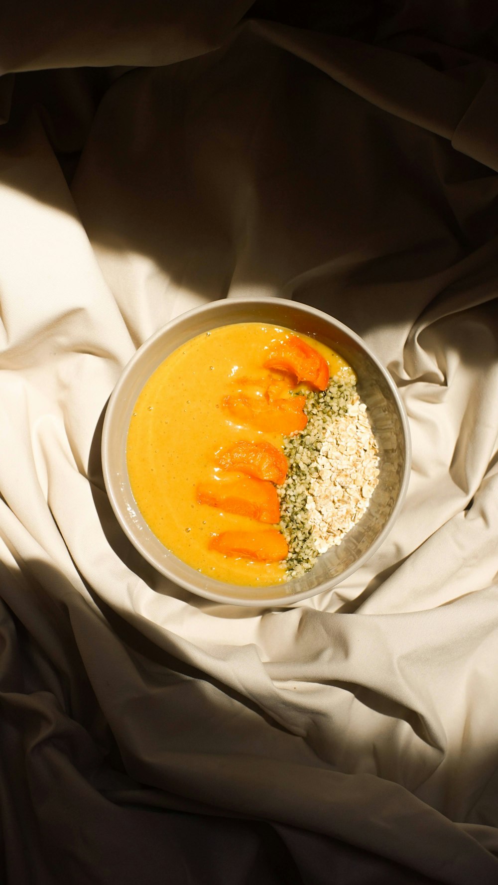 a bowl of carrot soup on a bed