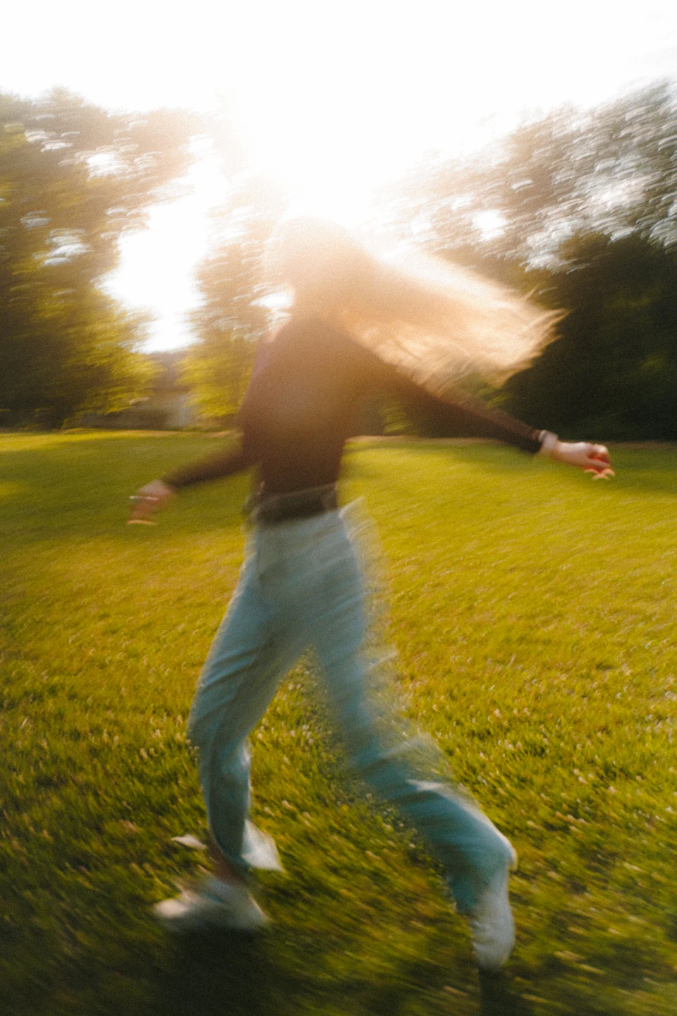 Runner in motion on grassy field with arms outstretched and legs slightly bent forward