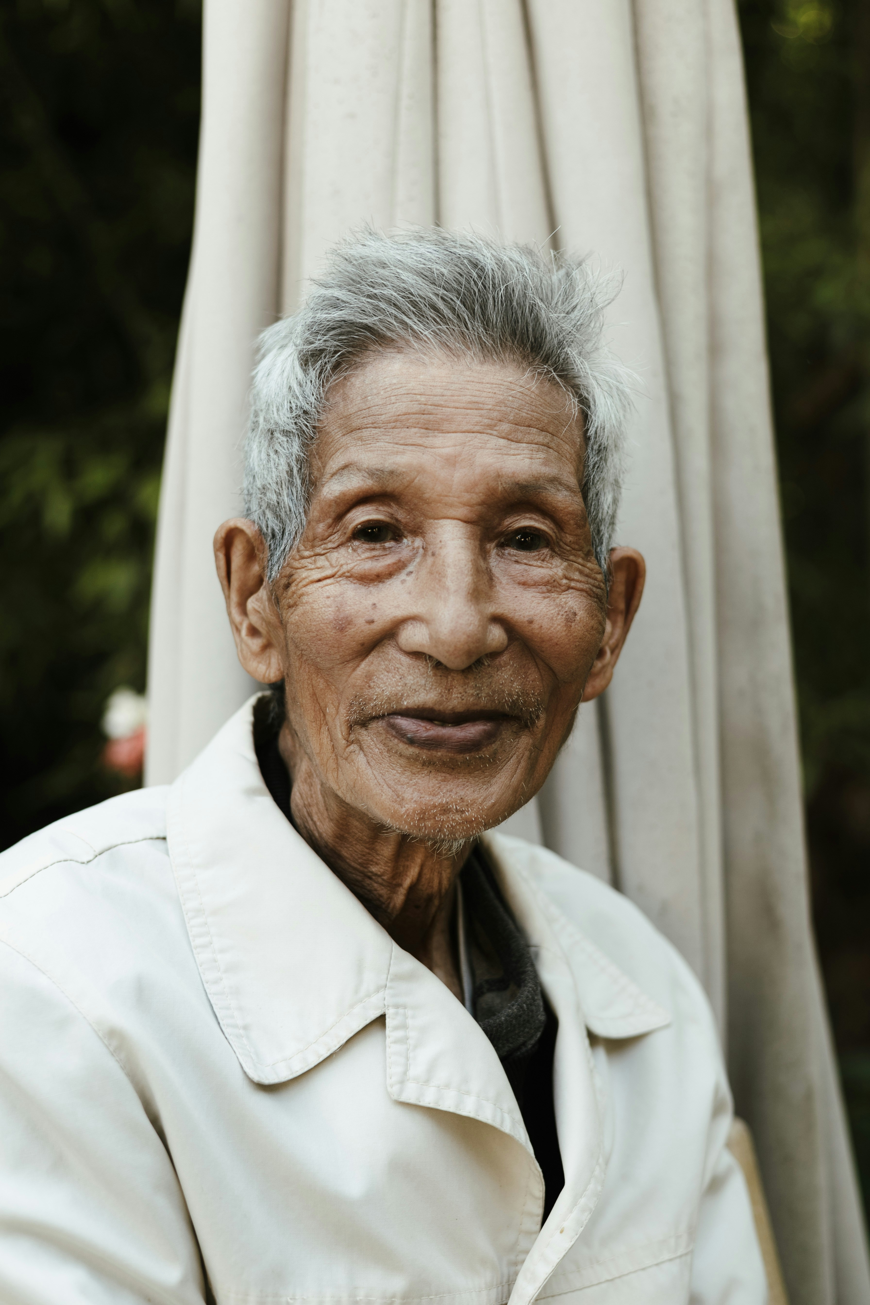 an old man with grey hair and a white coat