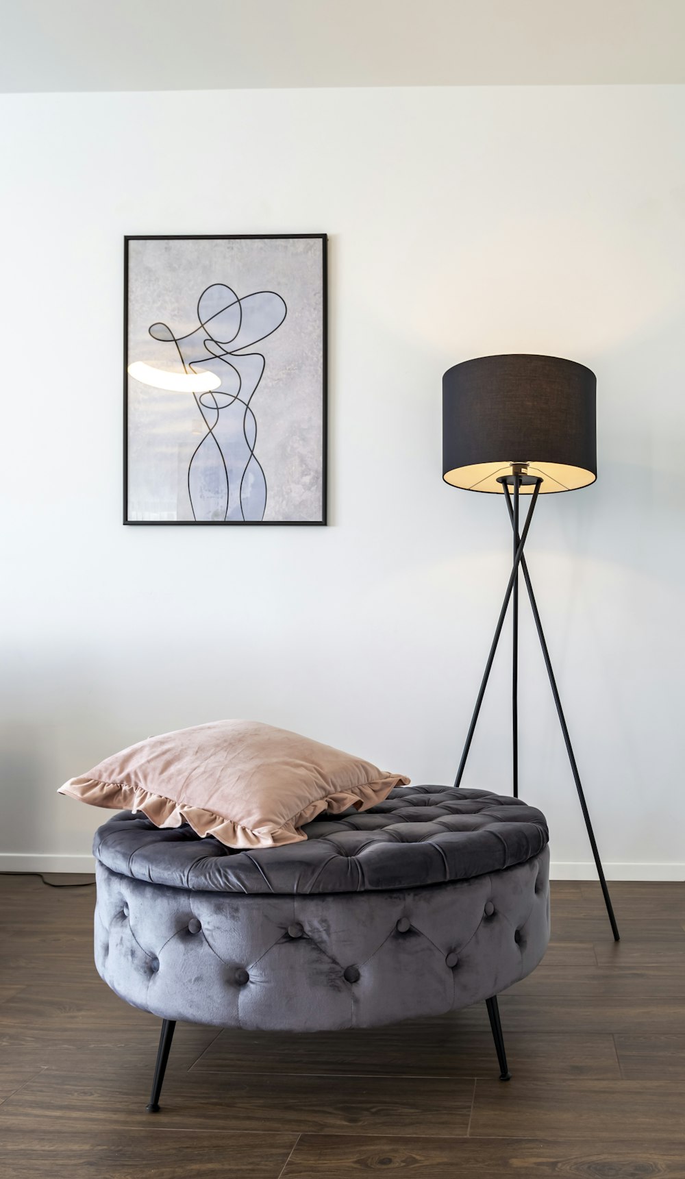 a bed with a round foot stool next to a lamp