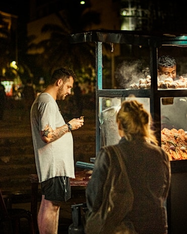 A candid shot of a street food vendor serving customers with a warm smile.
