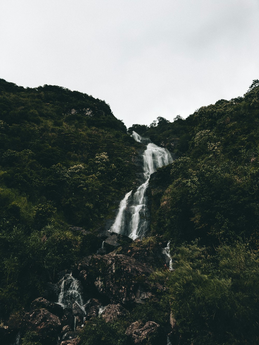 a very tall waterfall in the middle of a forest