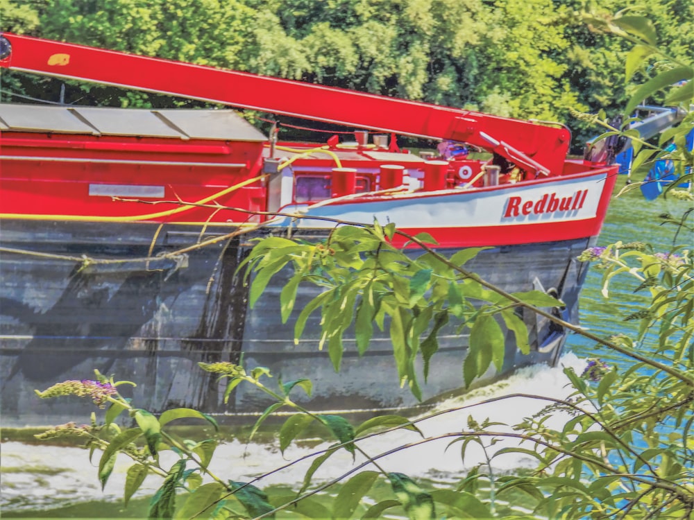 a red and white boat floating on top of a river