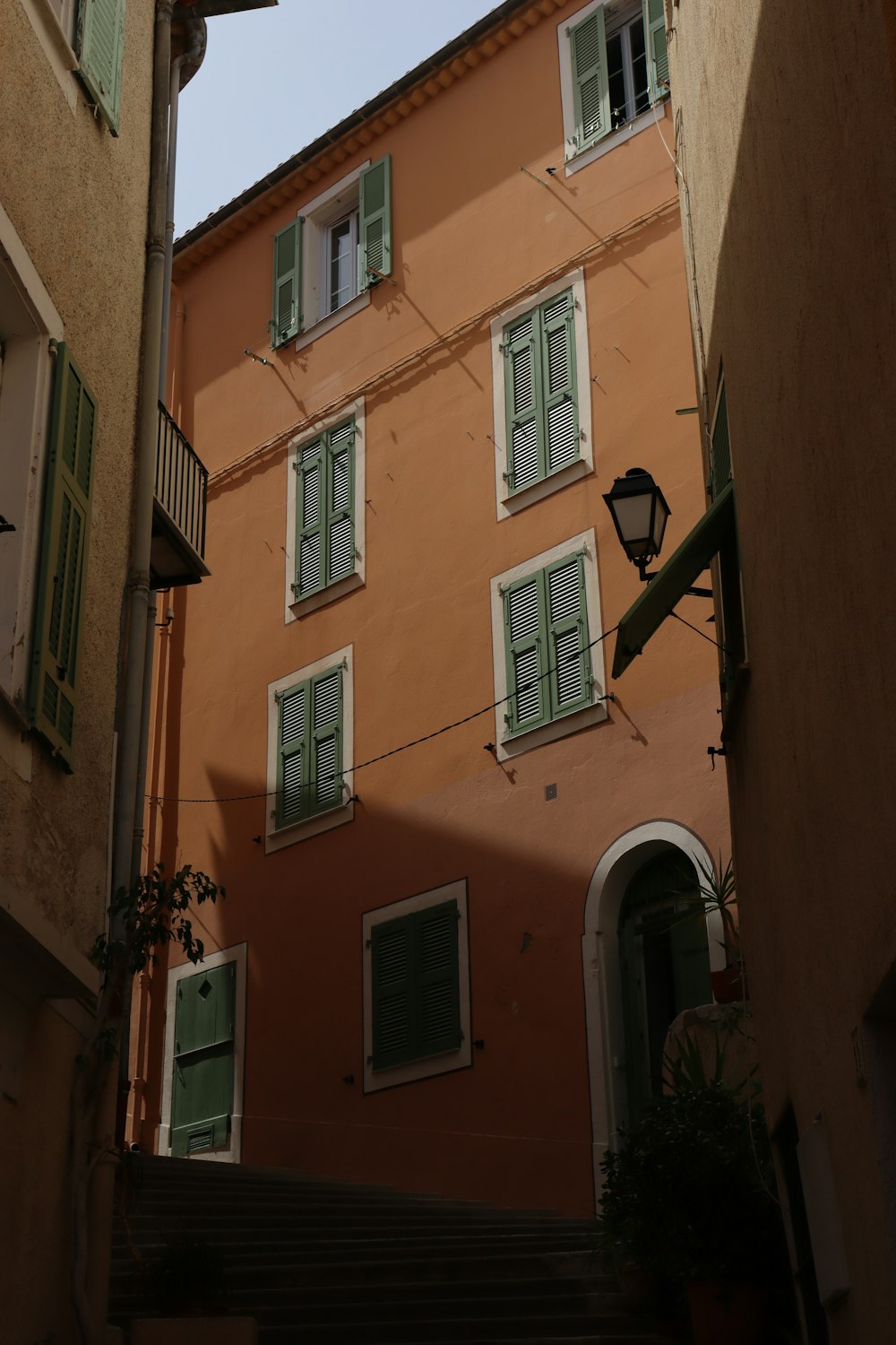 an orange building with green shutters and a street light