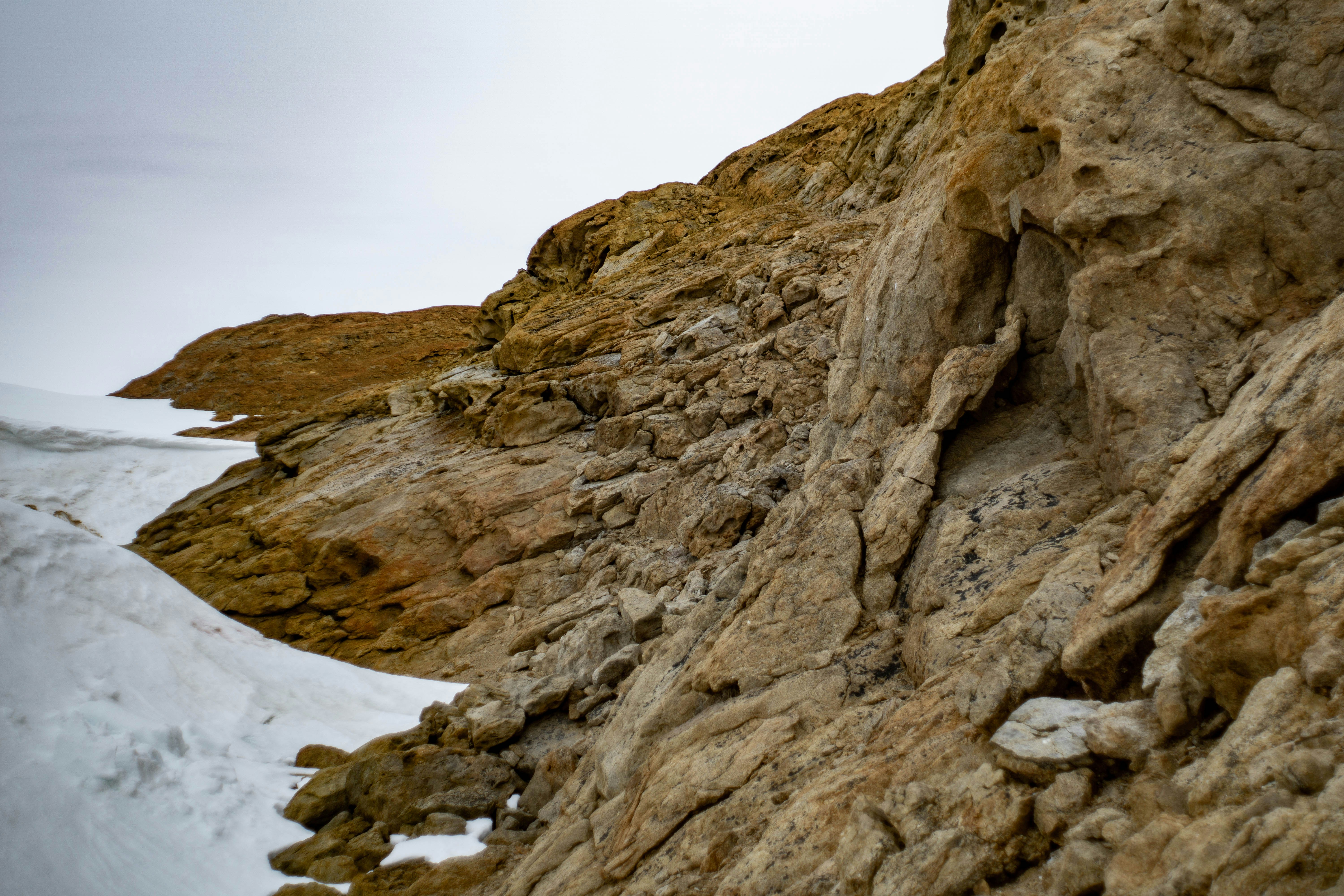 a person climbing up a mountain with a snowboard