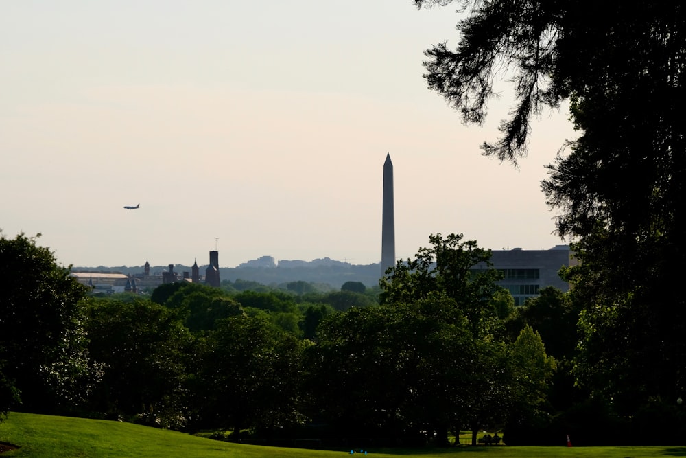 a plane flying over the washington monument in the distance