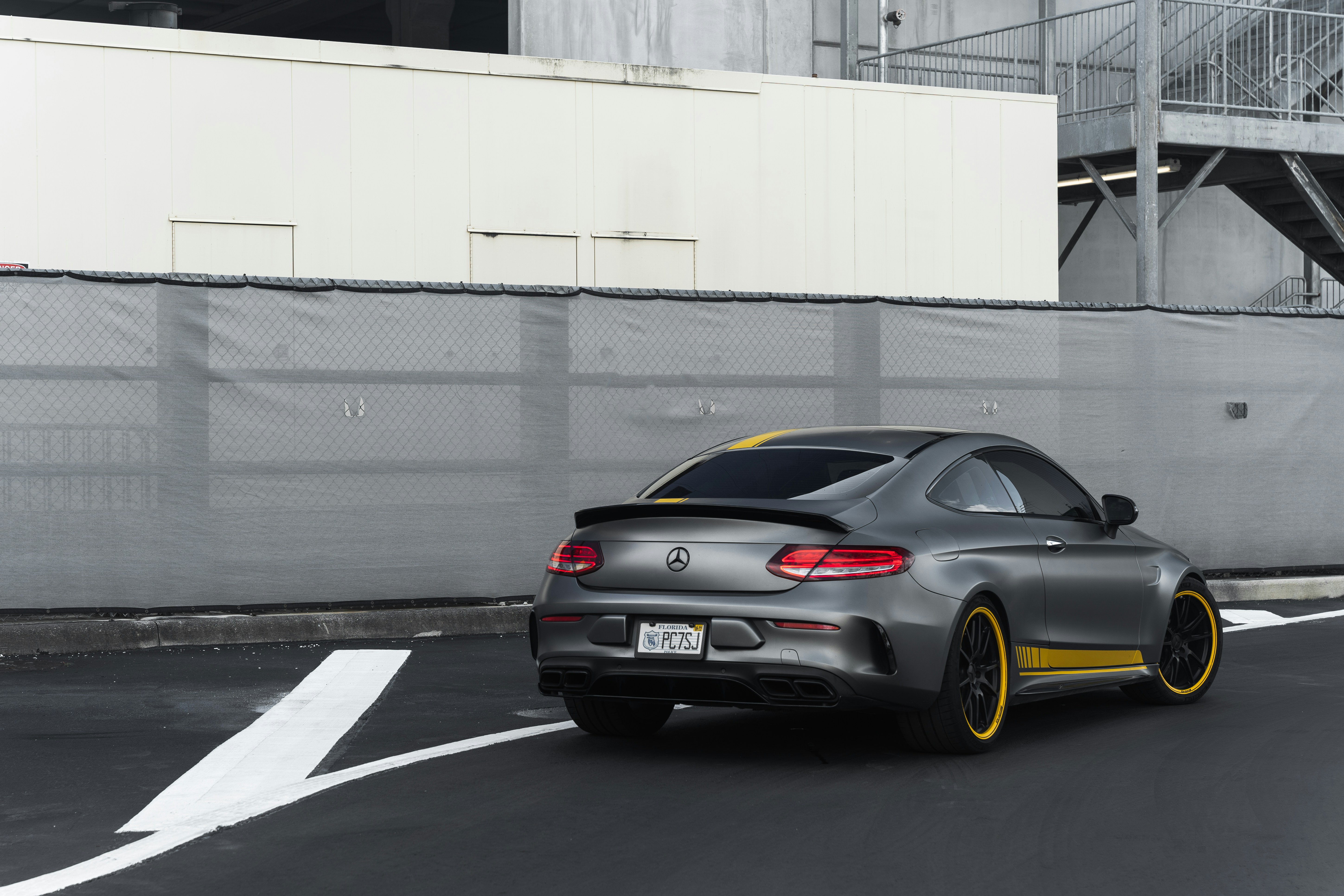 a silver car driving down a street next to a tall building