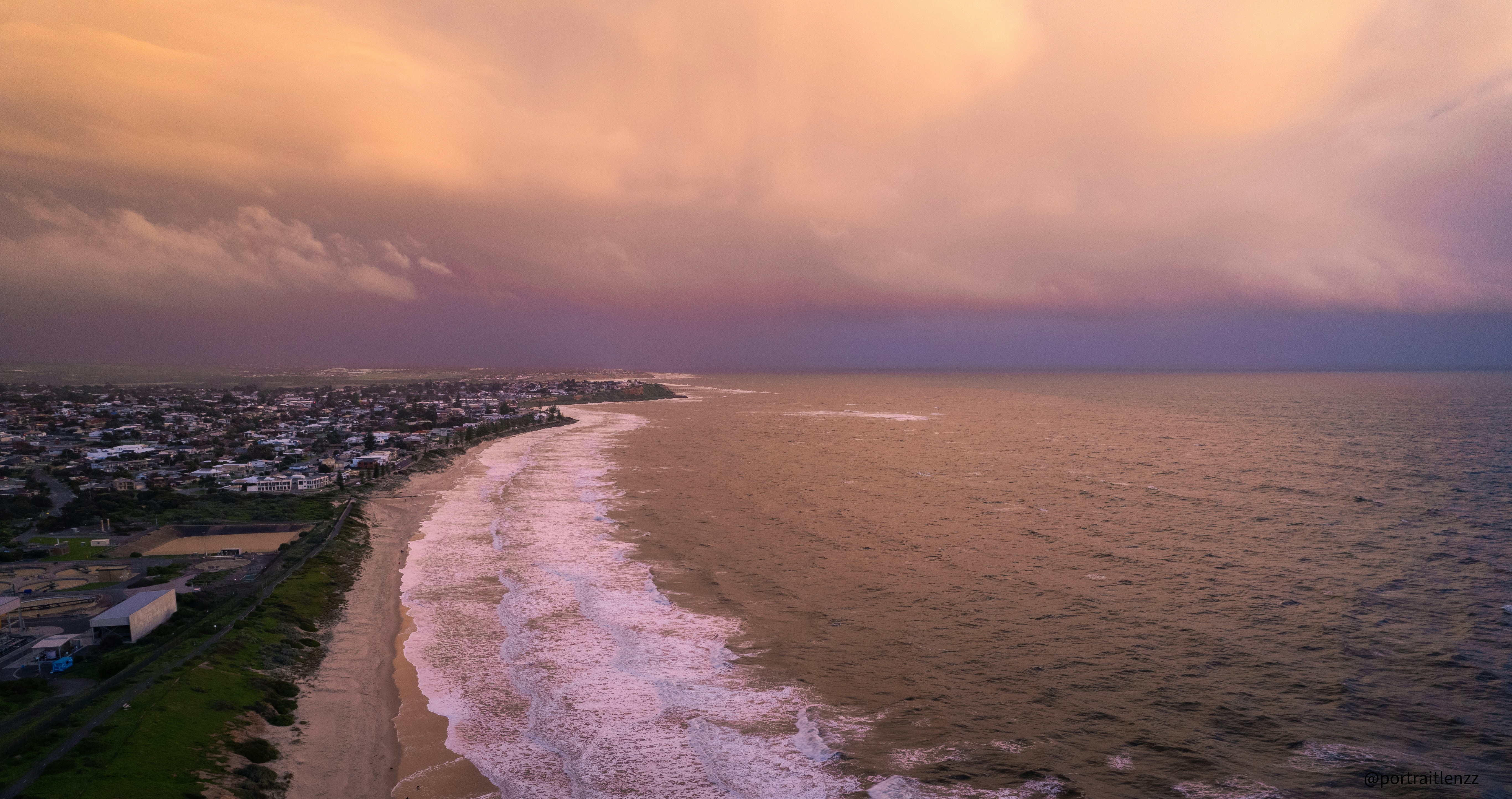 an aerial view of a beach and the ocean under a cloudy sky
