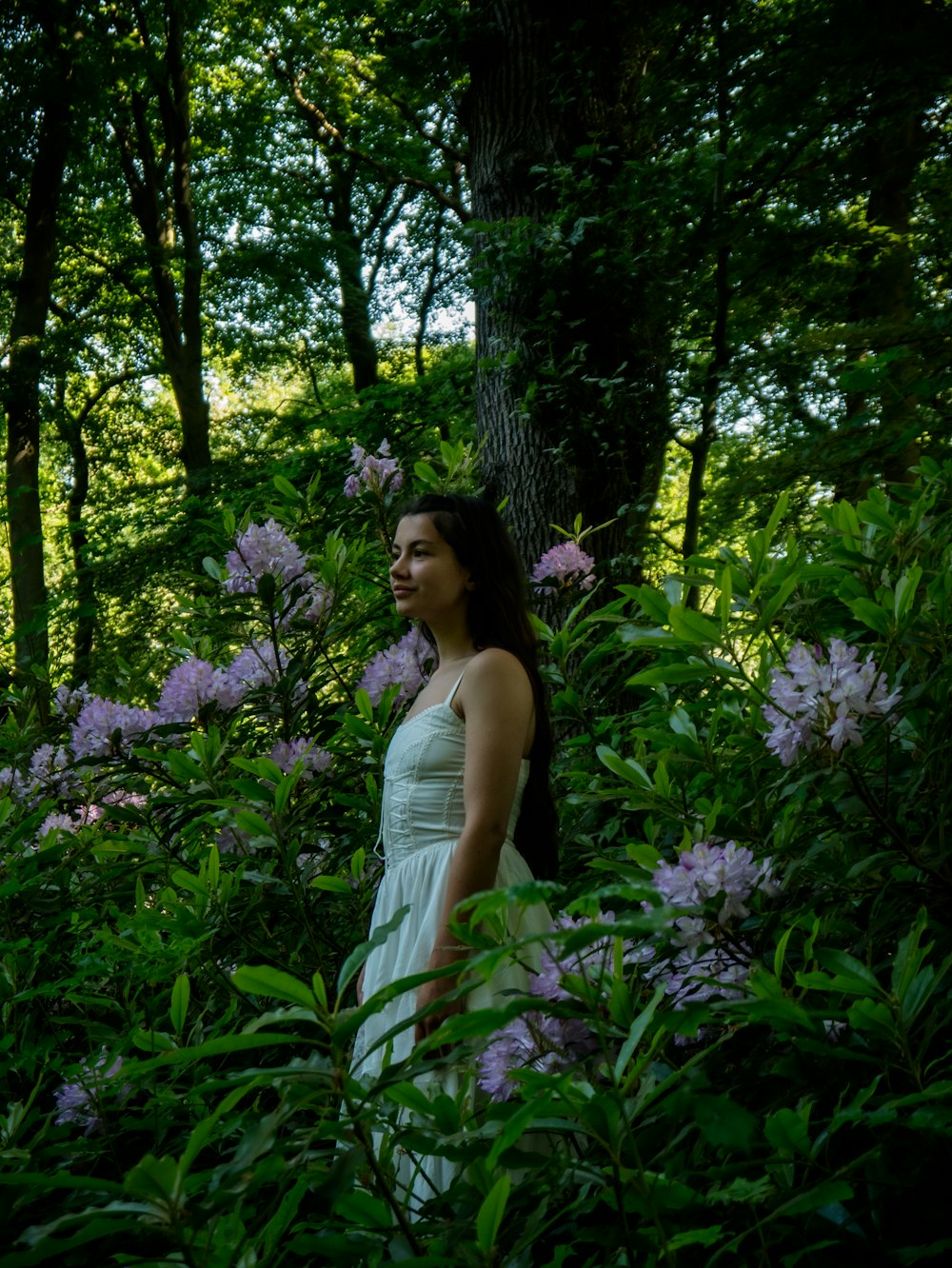 a woman in a white dress standing in a forest