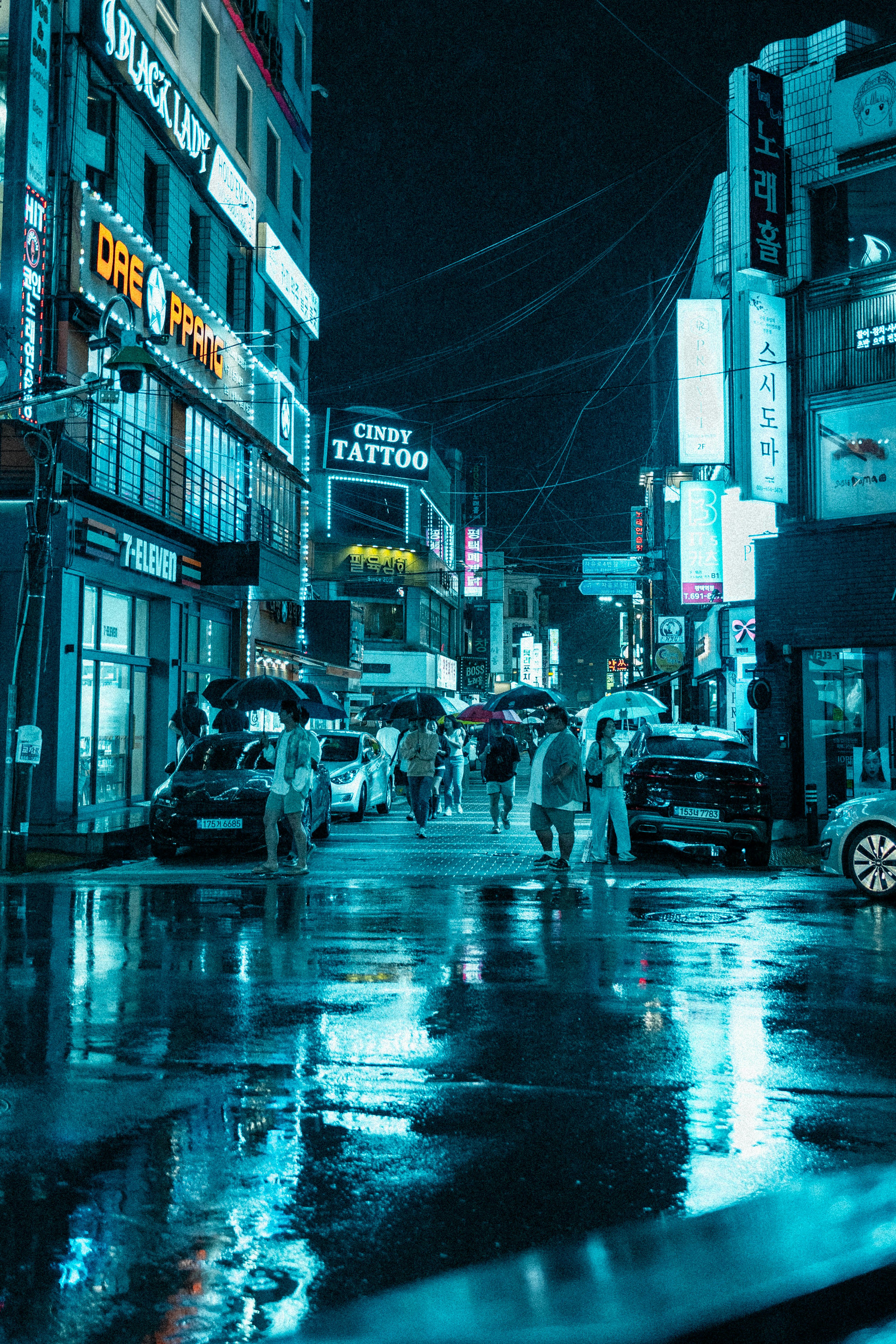 a group of people walking down a rain soaked street