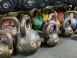 Set of kettlebells in varying weights lined up on a polished floor with ambient lighting.